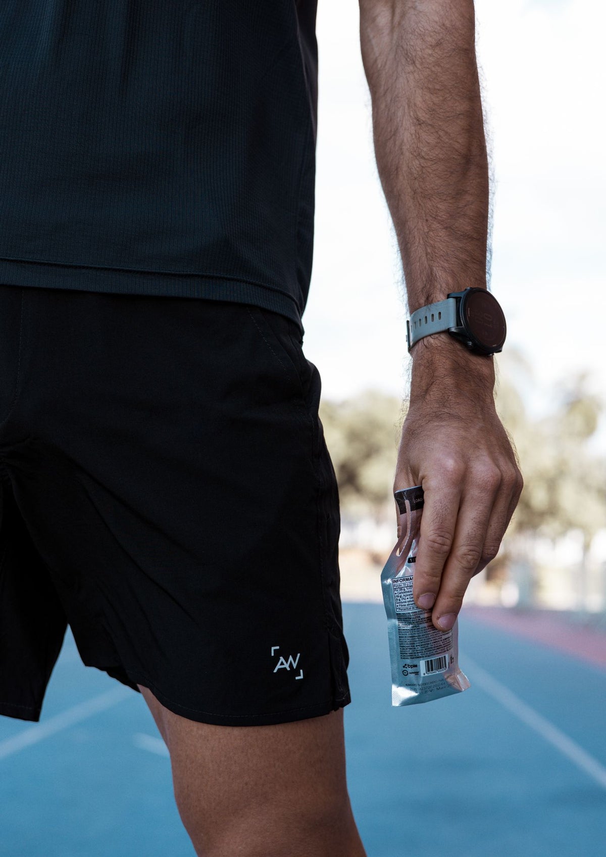 Athlete holding a foil energy gel packet on a running track